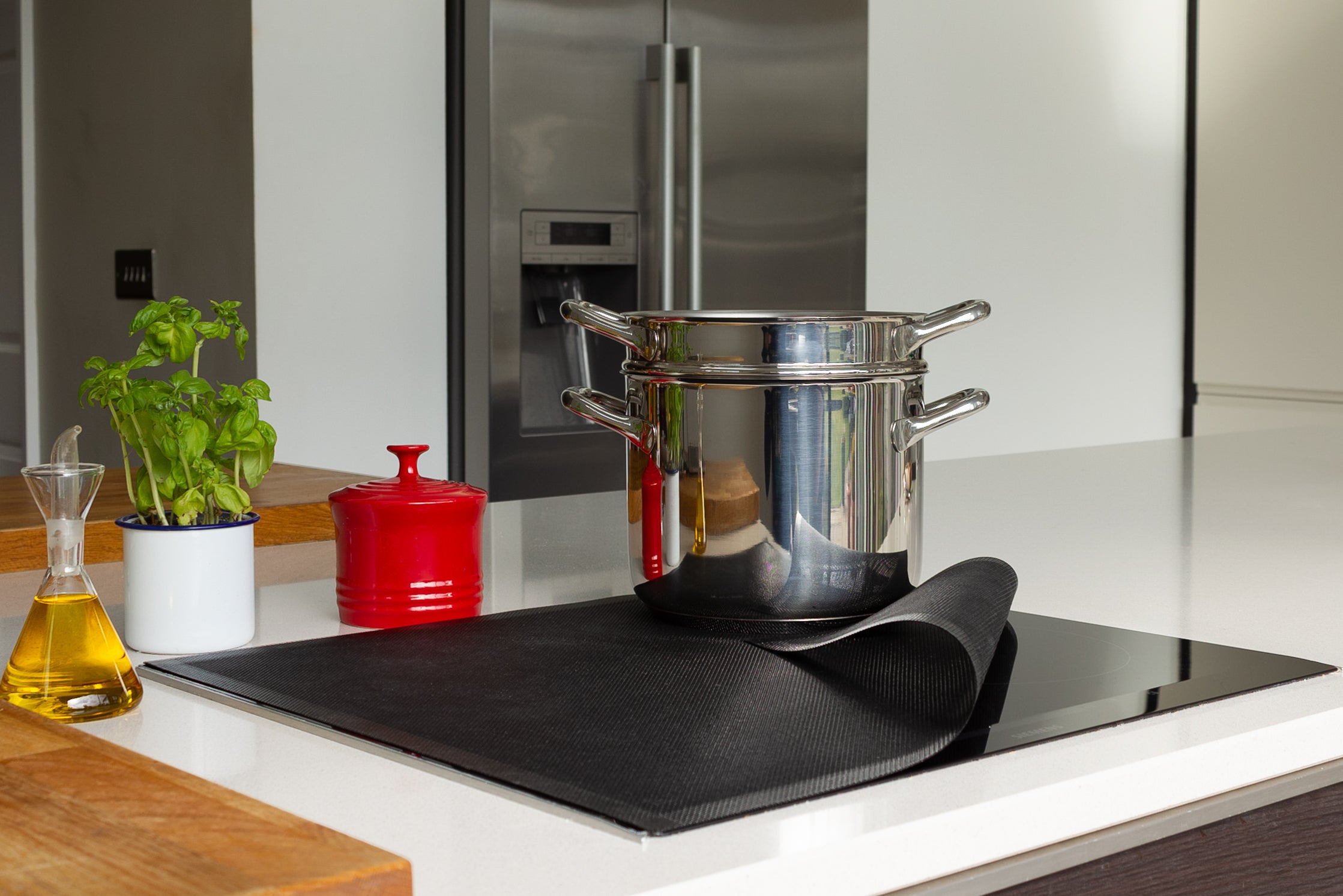 Stovetop with pot and pan on a Bake-O-Glide Induction Hob Protector in a modern kitchen