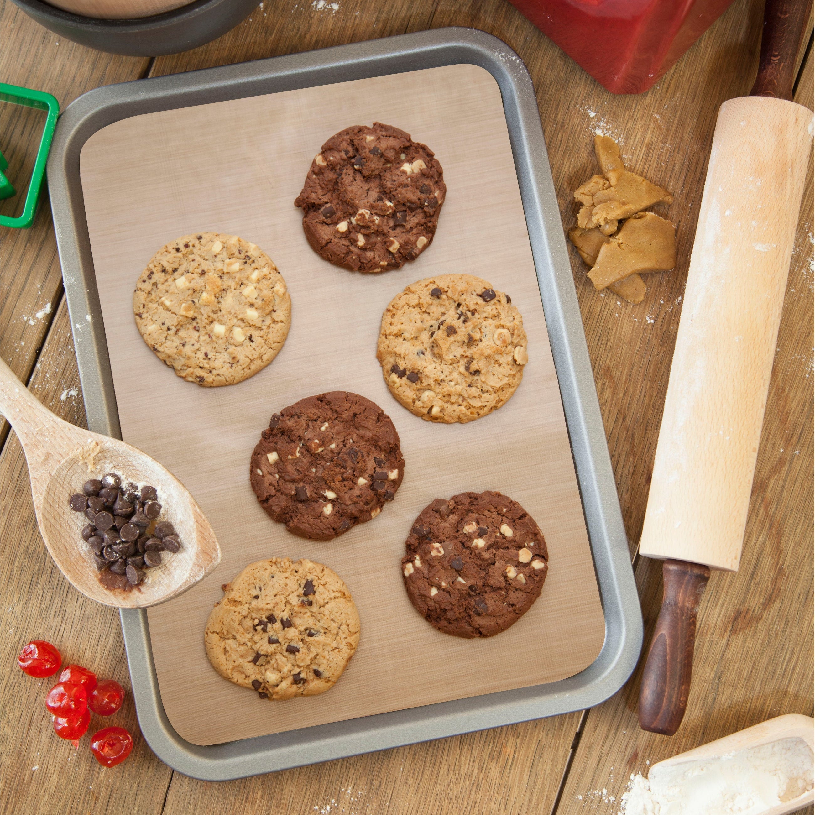 Assorted cookies on a reusable non-stick Bake-O-Glide® liner in a baking tray, with a rolling pin and chocolate chips