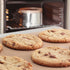 Chocolate chunk cookies baking on a reusable non-stick Bake-O-Glide® liner on a baking tray, cake tin in the oven behind